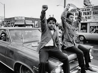 photo of men on car in parade supporting Chicano movement in U.S.